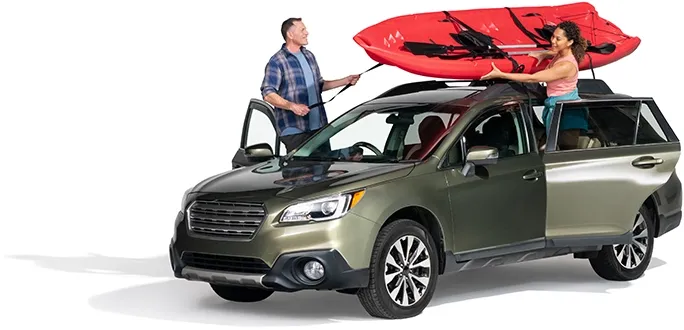 A couple secure a red raft atop their SUV